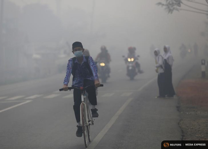A boy rides his bike in the haze along an Indonesian highway in late October, at the height of forest fires that blanketed much of Southeast Asia in a haze. (Photo by REUTERS/Darren Whiteside)