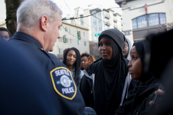 Captain Paul McDonaugh, commander of the Seattle Police Department’s East Precinct, talks with Hamza Warsame’s sister, Ikram, as the group stopped in front of the East Precinct building on 12th Avenue. He urged her and her family to share all of their grievances and concerns during their meeting with the Seattle Police Department tonight, according to Ikram Warsame. (Photo by Jovelle Tamayo.)