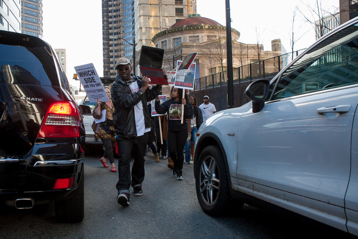Tehuti Dagray, owner of Freedom Outreach Radio and a representative of the Black Prisoners Caucus, marches through traffic in downtown Seattle during a demonstration for Che Taylor, who was shot and killed Sunday by Seattle Police. (Photo by Jovelle Tamayo.)