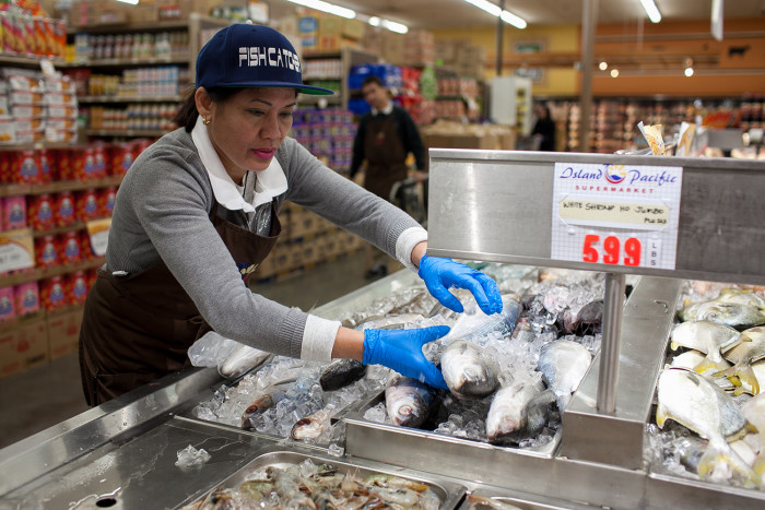 Amelda Orcejola handles seafood for a customer on February 24, 2016 at Island Pacific Market, a Filipino-inspired grocery store in Seattle’s Rainier Valley. (Photo by Jovelle Tamayo.)