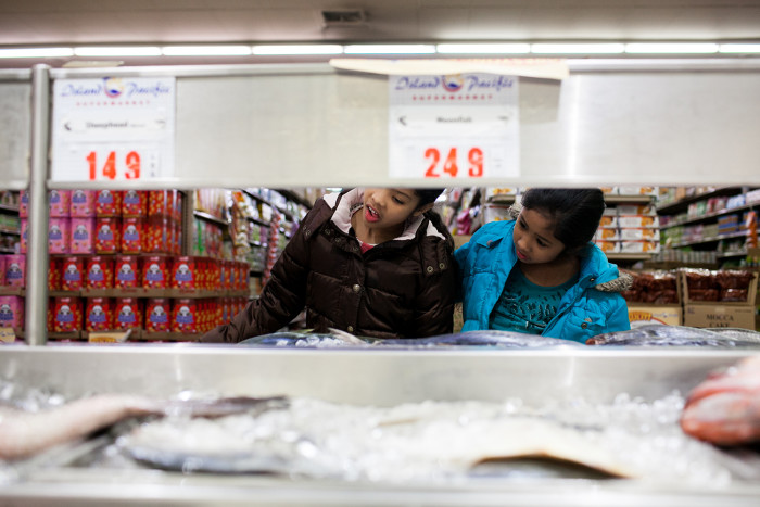 Dayana and Sheyla Aguilar examine fish while their mother shops on February 18, 2016 at Island Pacific Market, a Filipino-inspired grocery store in Seattle’s Rainier Valley. (Photo by Jovelle Tamayo.)