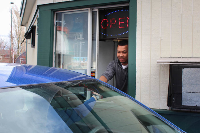 Abodolloh Zay serves a drink to a drive-through customer at First Cup Coffee. Fewer cars have come through during the months of construction. (Photo by Venice Buhain.)