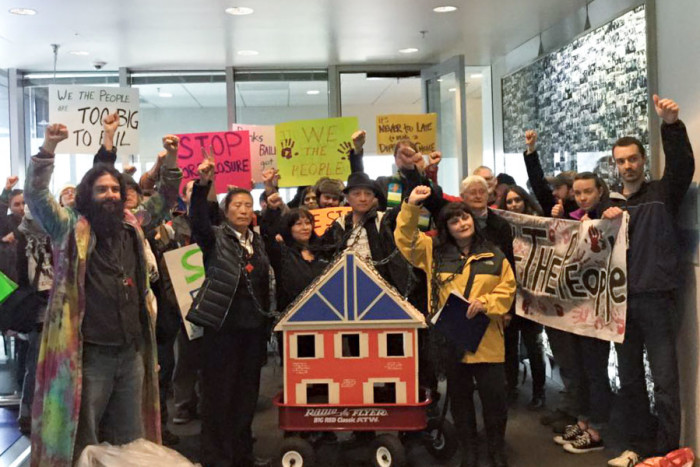Activists from SAFE and Valley & Mountain join Belgrano in chaining themselves to a model house that they carried to City Hall, the King County Recorder's Office and JP Morgan Chase offices.(Courtesy photo)