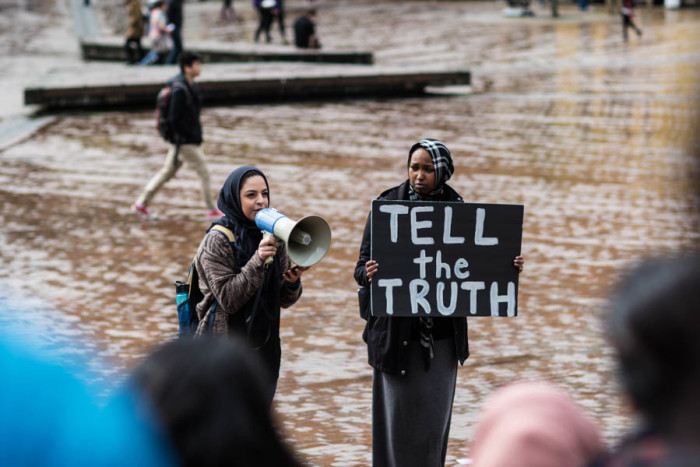 UW Bothell senior Isra Ayesh speaks at a vigil while organizer Najma Hassan holds a sign that reads "Tell the Truth." The vigil was hosted in honor of Mohamedtaha Omar, 23, Adam K. Mekki, 20, and Muhannad A. Tairab, 17, who were victims of an execution-style killing in Fort Wayne, Indiana. (Photo by Raisa Janjua)