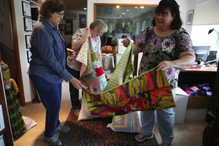 Jackie Lambert, left, Susan Schmidt and Brenda Pierce are part of a volunteer group assembling “baby boxes,” which include handmade quilts, in Seattle. (Photo by Ken Lambert for The Seattle Times)