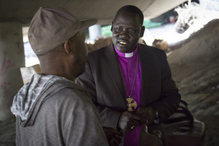 Rev. Bishop David Kuol of the Awerial Diocese of South Sudan talks with a resident of The Jungle underneath I-5. The Reverend is touring the United States and visiting with Sudanese who have resettled here, including several "Lost Boys" now living in the homeless encampment. (Photo by Sy Beam / The Seattle Times)