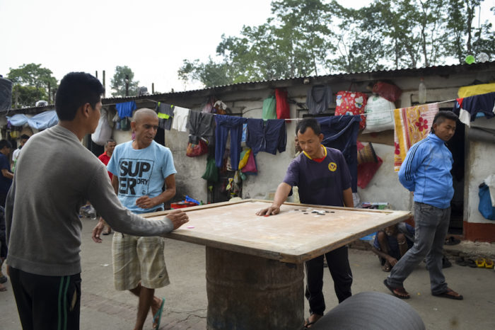 Shanta Lama, in dark blue shirt with yellow emblem, plays carrom, a board game in the courtyard at Kavre District Prison. (Photo by Kalpana Khanal for GPJ Nepal)