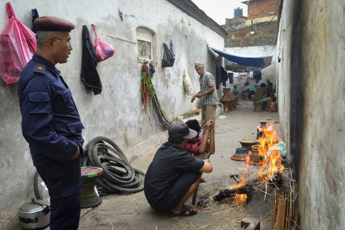Purna Bahadur Pradhan, 46, the police officer in charge of security at the prison, watches two prisoners cook. The officer visits the prison twice a day to monitor activities there. (Photo by Kalpana Khanal for GPJ Nepal)