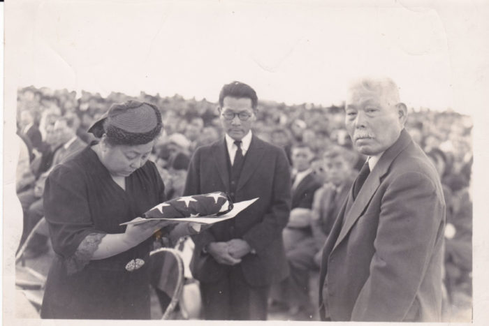 Tom Ikeda's grandparents Fred Suyekichi and Akino Kinoshita (left and center) receive a flag in honor of their son Staff Sergeant Francis “Bako” Kinoshita, killed in action in World War II, accompanied by a family friend. (Photo courtesy Tom Ikeda.)