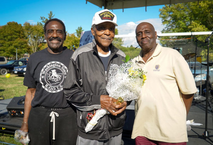 ROOTS Committee members Paul Mitchell and William Lowe present the oldest man at the picnic, 95 year old Clyde Robinson with flowers and a gold trophy.