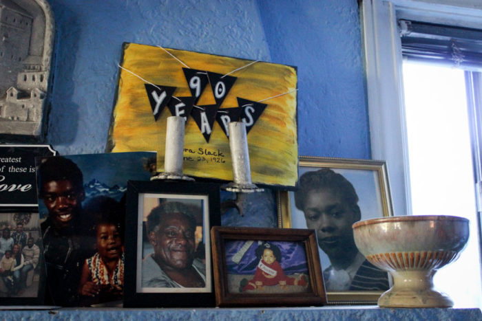 Photos of the Slack family on the mantle of their Central District home, including little painting made for Dora Slack's 90th birthday in June. (Photo by Alia Marsha)