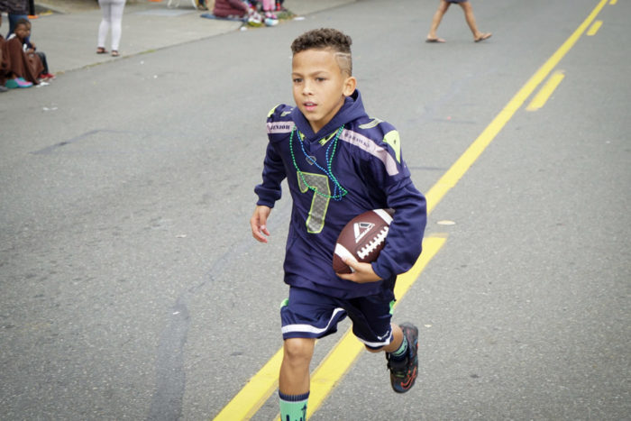 A Seattle Jr. Seahawks player runs to catch up to his teammates during the 2016 Umoja Fest Parade.
