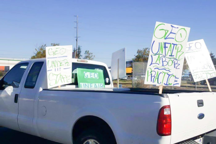 Employee cars and trucks parked outside of the Northwest Detention Center on Tuesday had picket signs charging "unfair labor practices" and understaffing" at the privately-run facility. (Photo by Victoria Mena)