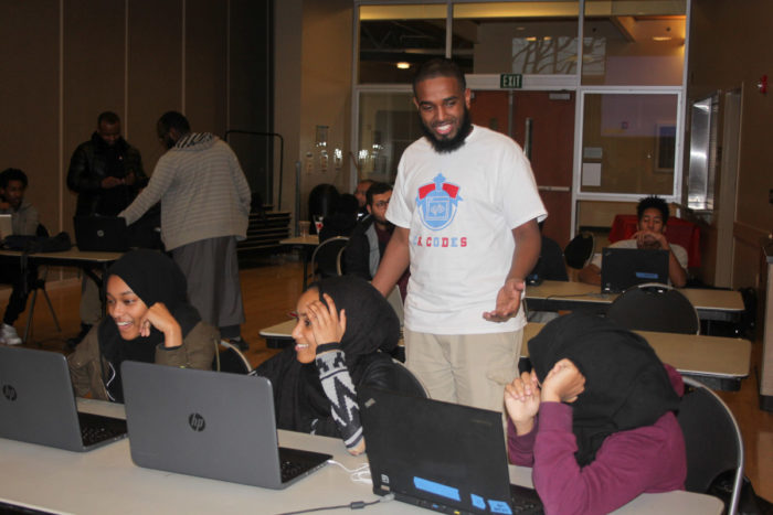 Volunteer Mukhtar Sharif helps Jemila Abdullah, Iftin Kedir and Munera Mohammed (from left) during a coding class for East African youth held by Companion Athletics. (Photo by Goorish Wibneh)